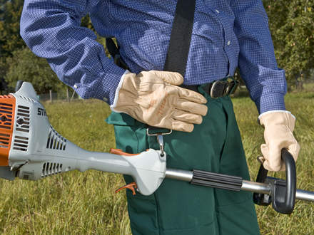 : First put on the shoulder strap and attach the hook to the carrying ring on the machine. The hook should be about a hand's width below your right hip.